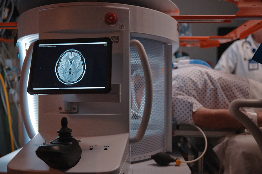The Swoop® AI-powered portable MR imaging system in an intensive care unit setting with a patient having their brain scanned and a brain image on the iPad display..
